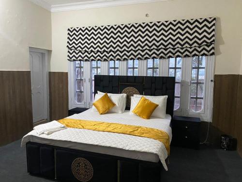um quarto com uma cama grande com almofadas amarelas e brancas em The Nook em Muzaffarabad