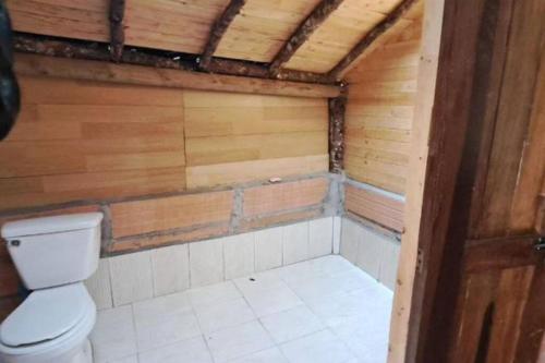 een badkamer met een toilet en een houten muur bij Eco Aldea Cabaña entre helechos in Medellín