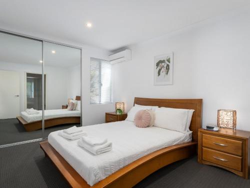 a bedroom with a large bed and a mirror at Three Bedroom, Two Bathroom Family Home in Coogee