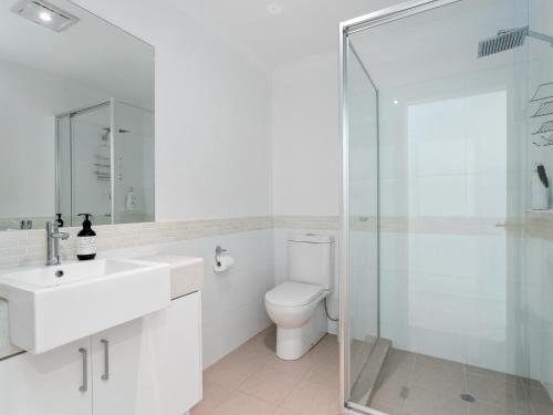 a white bathroom with a toilet and a glass shower at Three Bedroom, Two Bathroom Family Home in Coogee