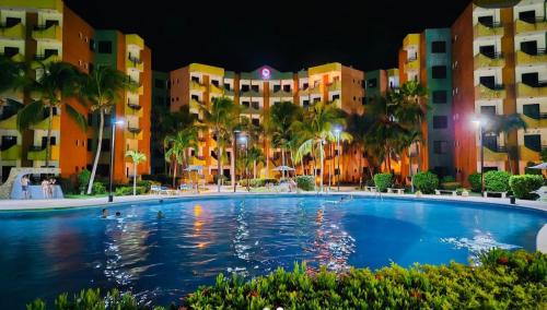 ein großer Pool vor den Gebäuden in der Nacht in der Unterkunft Arriendo Ciudad Flamingo in El Marite
