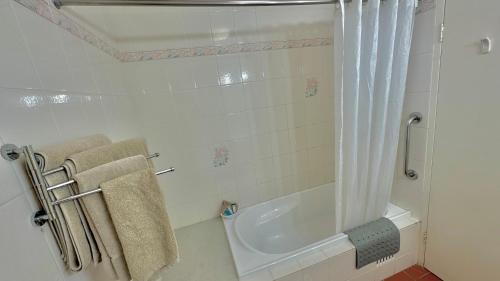 a bathroom with a tub and a shower with towels at Golden Grain Motor Inn in Tamworth