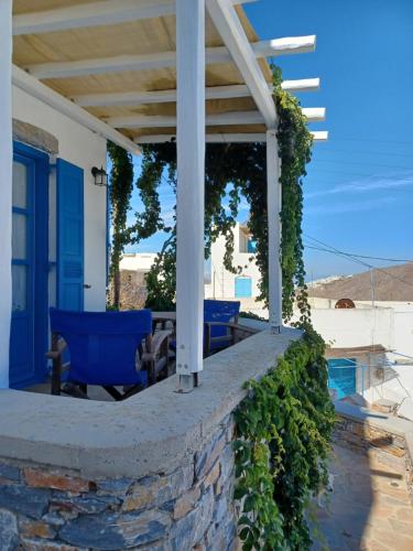 a patio with blue chairs on a stone wall at Vicky's Studios in Órmos Aiyialís