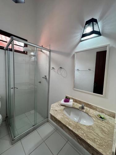 a bathroom with a sink and a glass shower at Pousada Alforria in Búzios