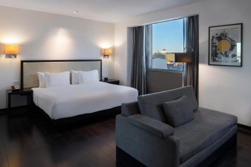 a hotel room with a bed and a chair at Hilton DoubleTree Guadalajara Centro Historico in Guadalajara
