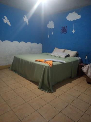 Cama en habitación azul con nubes en la pared en Casa Zope, en Panajachel