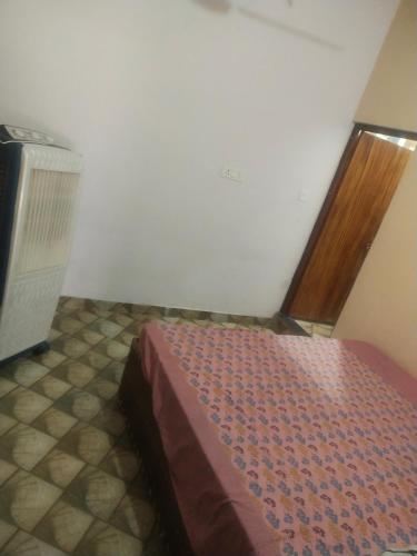 Schlafzimmer mit einem Bett und einer Holztür in der Unterkunft Gaurangi seva sadan in Mathura