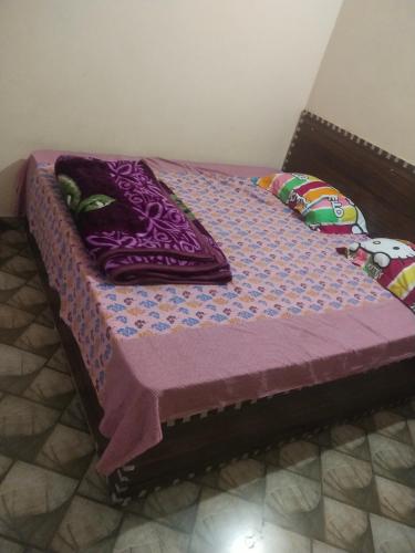 a bed with a purple quilt and pillows on it at Gaurangi seva sadan in Mathura
