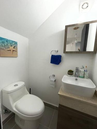 a white bathroom with a toilet and a sink at Increíble Casa con alberca y club de playa in Barra Vieja