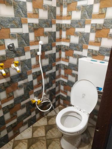 a bathroom with a toilet and a tiled wall at Gaurangi seva sadan in Mathura