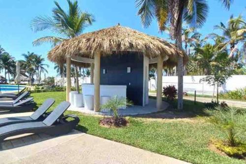 a gazebo with two lounge chairs in the grass at Increíble Casa con alberca y club de playa in Barra Vieja