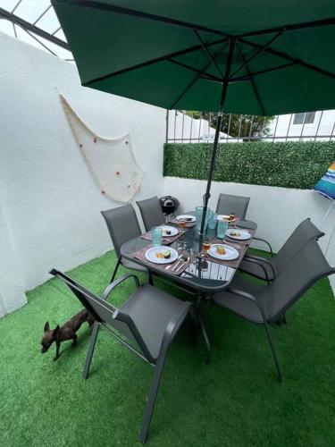 a table and chairs with a dog under an umbrella at Increíble Casa con alberca y club de playa in Barra Vieja