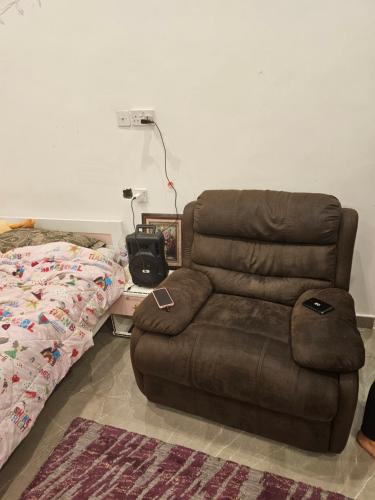 un divano marrone in un soggiorno accanto a un letto di New Naseem block 3 a Al Jahra