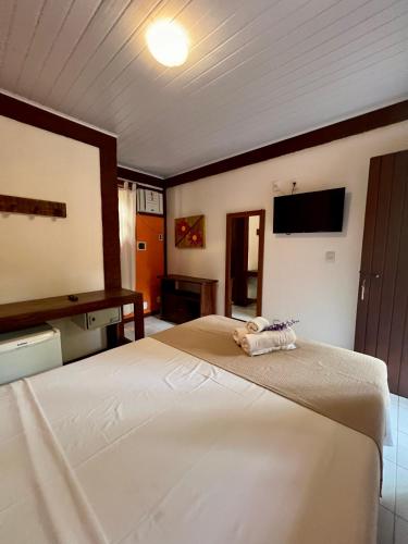 a bedroom with a large white bed and a television at Pousada Alforria in Búzios