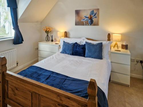 a bedroom with a large bed with blue pillows at Bluebell Lodge in Long Stowe