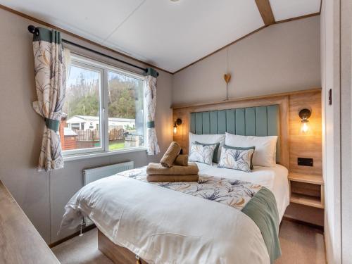 a bedroom with a bed with a teddy bear on it at Fir Tree Lodge in Aviemore