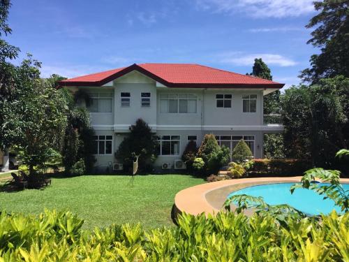 a large white house with a red roof at Camiguin Lanzones Resort in Mambajao
