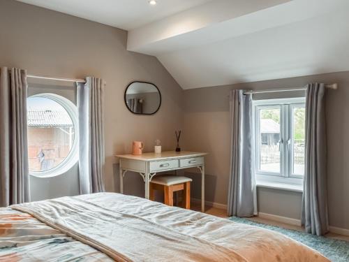 a bedroom with a bed and a desk and a window at Brook Farm Cottage in Nantwich