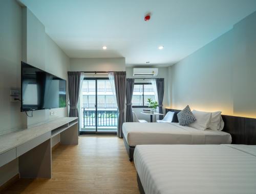 um quarto de hotel com duas camas e uma televisão de ecrã plano em College Haus Rangnam em Bangkok