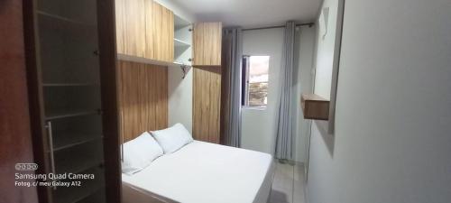 a small bedroom with a white bed and a glass door at Apartamento in Belo Horizonte