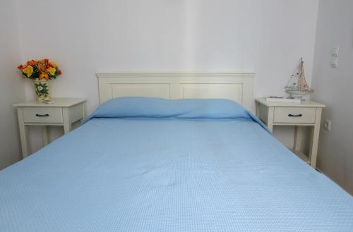 a bedroom with a blue bed with two night stands at Vicky's Studios in Órmos Aiyialís