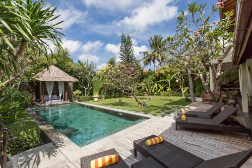 een achtertuin met een zwembad en een tuin bij Villa Balidamai by Nagisa Bali in Kerobokan