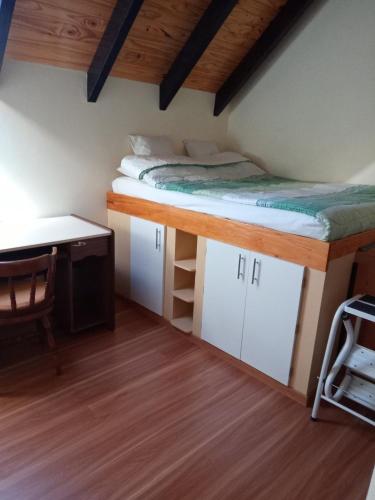 a bed in a room with a desk and a bed at Alojamiento Dihlmann in Dina Huapi