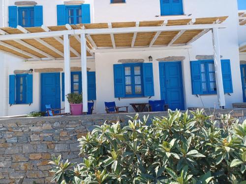 a house with blue doors and a stone wall at Vicky's Studios in Órmos Aiyialís