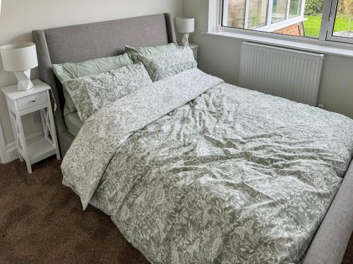 1 dormitorio con cama con edredón y almohadas blancos en Commonside Cottage en Lytham St Annes