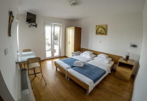 a bedroom with two beds and a desk and a table at Apartments Car in Rab