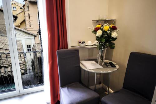 un vaso di fiori seduto su un tavolo accanto a una finestra di The Roman Empire Guesthouse a Roma