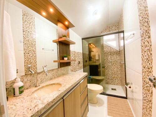 een badkamer met een wastafel, een douche en een toilet bij Aconchego do Valle in Gramado