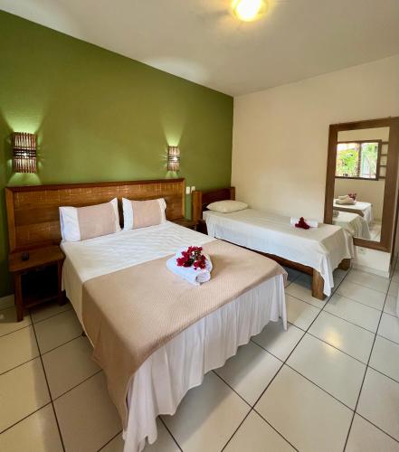 a hotel room with two beds with flowers on them at Pousada Alforria in Búzios