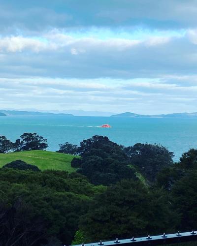 a view of the ocean with a boat in the distance at La Bodega Waiheke Island in Surfdale