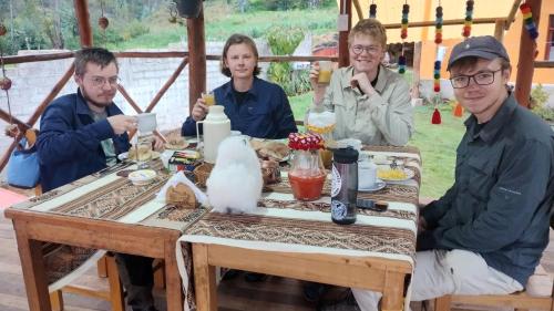 a group of people sitting around a table at the wooden house choquequirao in Cachora