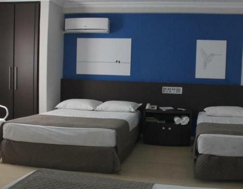 a bedroom with two beds and a blue wall at Abbas Hotel in Uberlândia