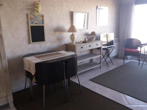 ein Wohnzimmer mit einem Tisch und einem Schreibtisch mit Stühlen in der Unterkunft Studio Les Sables-d'Olonne, 1 pièce, 3 personnes - FR-1-331-202 in Les Sables-dʼOlonne