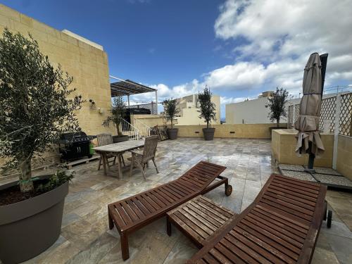 un patio avec deux bancs, une table et un grill dans l'établissement Ta' Pinu Spa Suite - Luxury Heritage Living, à Żebbuġ