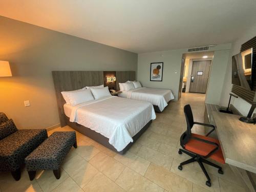 a hotel room with two beds and a chair at Holiday Inn Express Mérida by IHG in Mérida