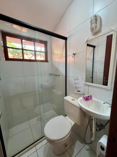 a white bathroom with a toilet and a sink at Pousada Alforria in Búzios