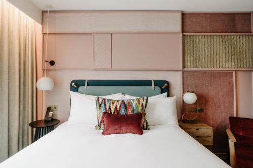 a bedroom with a bed with white sheets and red pillows at The Halyard Liverpool, Vignette Collection by IHG in Liverpool