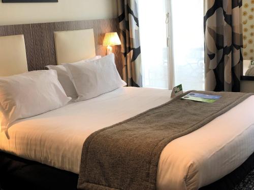 パリにあるHoliday Inn Paris Opéra - Grands Boulevards, an IHG Hotelのベッドルーム1室(大型ベッド1台、白いシーツ、枕付)