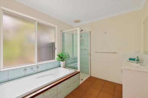 a bathroom with a tub and a shower and a sink at Sky Mirror Cottage in Rhyll