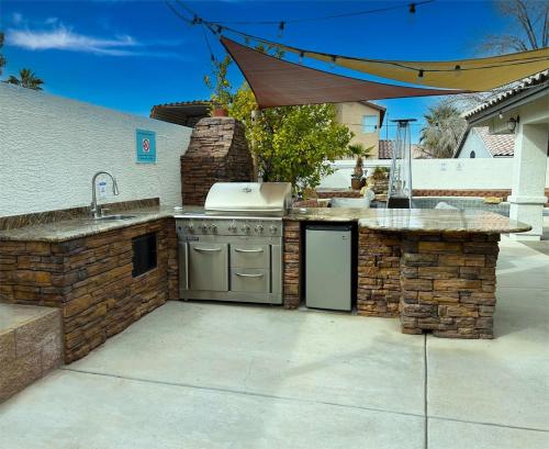 an outdoor kitchen with a sink and a stove at Ultimate Vacation: A Luxurious Oasis with a Pool! in Las Vegas