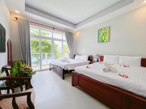 a bedroom with two beds and a large window at Sand Beach Resort in Mui Ne