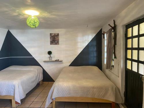 two beds in a room with blue and white walls at Casa Nopal Tu casa vacacional tipo hotel in Creel