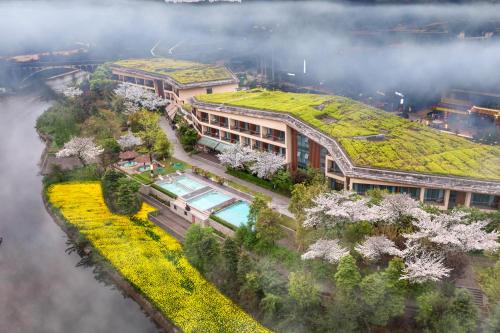 a building with a green roof with trees on it at Holiday Inn Express Emei Mountain by IHG in Emeishan
