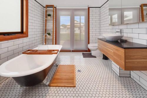 y baño con bañera, lavabo y aseo. en Stanley Stay - Adelaide 3 Bdrm, Central Location, WiFi, en Woodville