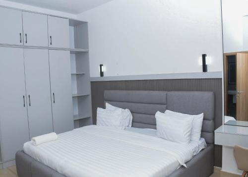 um quarto com uma grande cama branca com almofadas brancas em Margi Homes em Apapa Eleko