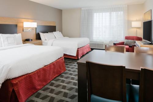a hotel room with two beds and a desk at TownePlace Suites by Marriott Kansas City Airport in Kansas City